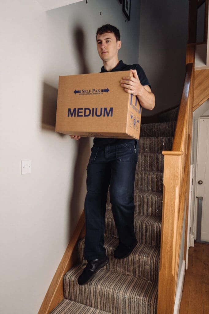 a man going down on a stairs carrying one box